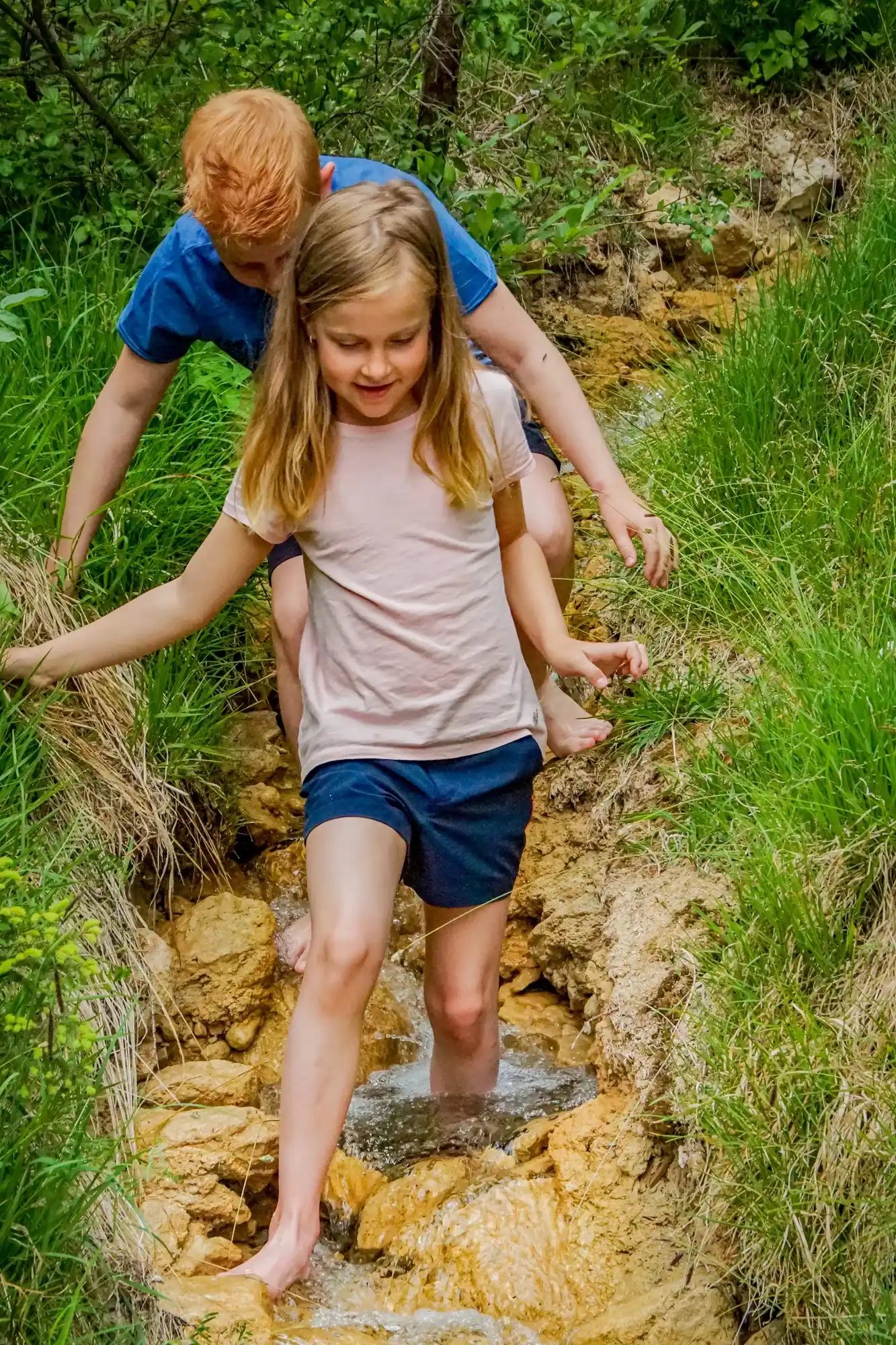 Children explore a small forest stream barefoot in the Lechtal